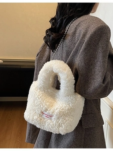 Borsa a secchiello in peluche bianca con tracolla a catena indossata con cappotto