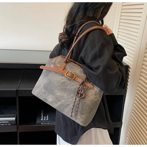 Detail der Vintage-Canvas-Tasche in Grau mit braunen Ledergriffen am Modell
