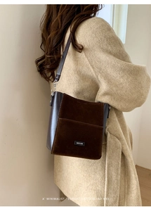 Detail of dark brown bucket bag with NO FILTER label and suede paneling on coat