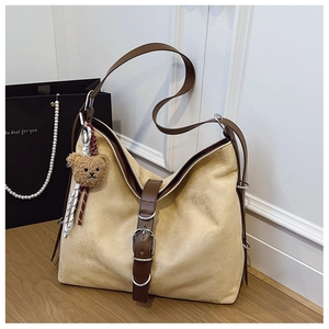 Detailed macro view of khaki suede tote bag with leather strap and bear plush charm