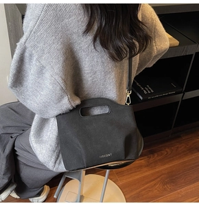 Detail view of black textured bucket bag with oval handle and adjustable shoulder strap