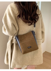 Détail du sac seau vintage en daim marron avec logo NO FILTER sur un manteau beige
