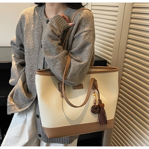 Detail of lychee pattern leather tote bag with elegant tassel charm and stitching