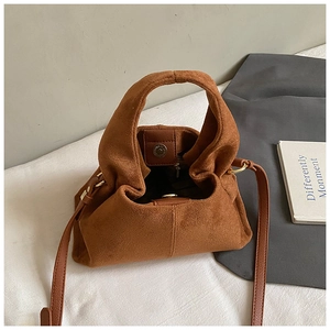 Detailed view of brown suede handbag with soft pleats and magnetic closure strap