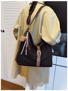 Detail view of large black matte hobo bag with brown leather strap and bear charm decoration
