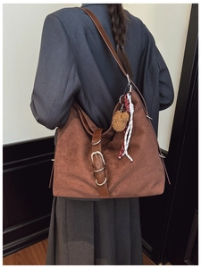 Detail of a large brown hobo bag with teddy charm on a model for casual commuting look