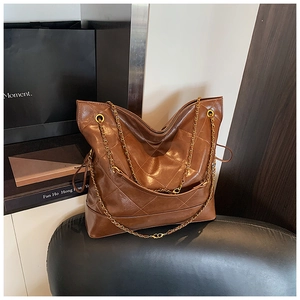 Detail of a brown quilted tote bag with golden chain straps and drawstring adjustment