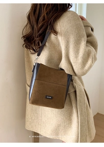 Detail shot of a retro crossbody bucket bag in brown suede and leather on a model outfit