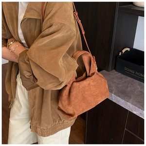 Detail showing soft matte faux suede texture and adjustable strap of the brown bucket bag