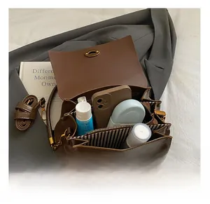 Détail du sac bandoulière en daim marron avec trois compartiments et doublure rayée