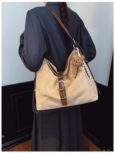 Detail of vintage suede tote bag with leather strap, buckle, and cute bear charm