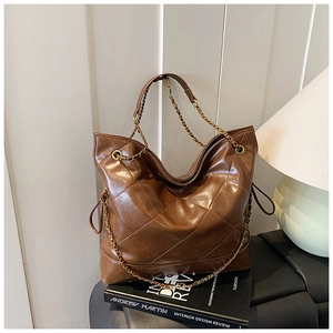 Detailed close-up of brown quilted tote bag with golden chain strap and drawstring accents