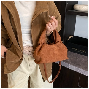 Detailed texture of brown suede bucket bag with adjustable leather shoulder strap