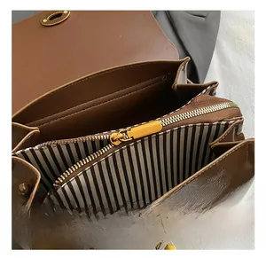 Gros plan intérieur du sac marron avec doublure rayée noire et blanche et détails dorés