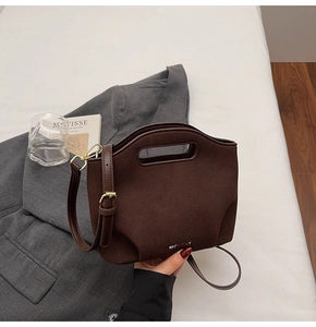 Detailed view of dark brown suede bucket bag with cut-out handle and metal logo