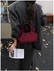 Chic burgundy frosted bucket bag styled with a dark blazer and newspaper props