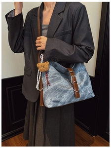 Close-up of marble-textured canvas tote bag with brown leather strap and plush bear charm