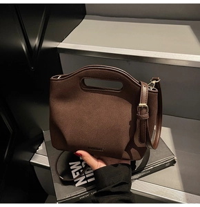 Detail of dark brown suede bucket bag with adjustable leather strap and metal buckle