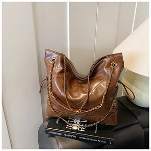 Detail of quilted caramel brown tote bag with gold chain strap and drawstring design