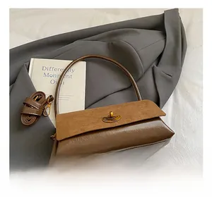Détail du sac bi-matière en daim et cuir avec fermoir rotatif sur un blazer gris