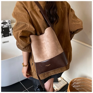 Detail of retro suede bucket bag showing contrast stitching and brand logo on leather