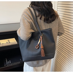Classic black leather tote bag with stylish brown fringe and vintage bead tassel detail