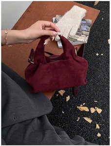 Detail view of burgundy frosted bucket bag with suede texture and golden metal hardware