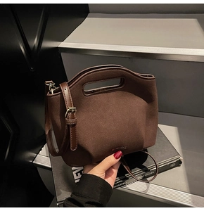 Detail view of the dark brown matte suede texture and hollow handle on this bucket bag