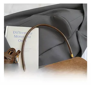 Détail d'un sac à main en daim marron avec fermoir tournant doré et poignée lisse