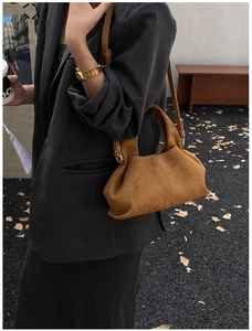 Close-up of a brown suede bucket bag with drawstring detail on a street setting