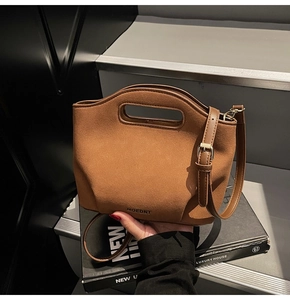 Detailed view of brown faux suede bucket bag featuring hollow handle and MOEDNT logo