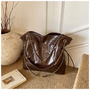 Detail view of dark brown quilted tote bag with golden chain strap and glossy PU finish