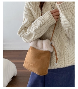 Detail view of brown suede bucket bag with plush faux fur trim and embroidered logo