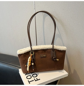 Détail du cabas en daim marron café avec bordure en fausse fourrure blanche et gland perlé
