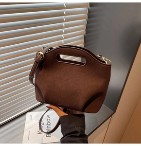 Detail of dark brown matte leather bucket bag with debossed logo and gold hardware