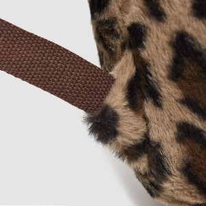Detailed close-up of leopard print plush backpack with reinforced brown nylon shoulder strap