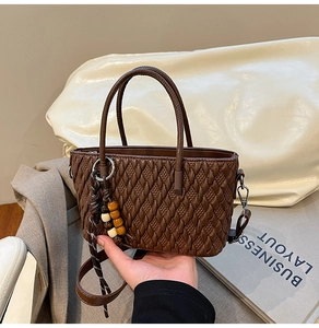Detailansicht der braunen Bucket Bag mit Webmuster, Holzperlen-Anhänger und Riemen