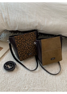 Close-up of leopard print and olive green suede bucket bags with brown leather details