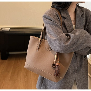 Detail of brown litchi pattern leather tote bag with stylish tassel and bead charm
