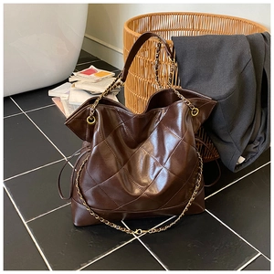 Close-up of brown quilted tote bag featuring gold chain strap and drawstring detail