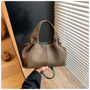 Detailed view of the dark brown suede bucket bag with contrast green handle stitching