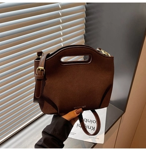 Detail of a brown suede bucket bag featuring a unique cutout handle and gold hardware