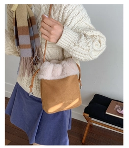 Detail of suede bucket bag with plush white trim and drawstring in cozy home setting