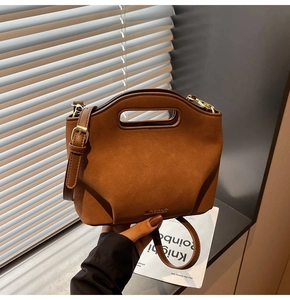 Detail of brown matte texture bag with cutout handle and gold hardware on shoulder strap