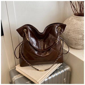 Detailed macro view of deep brown quilted tote bag with golden chain straps