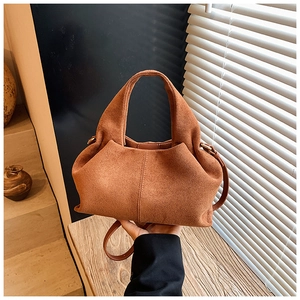 Detail of caramel brown suede bucket bag featuring elegant folded pleats and soft texture