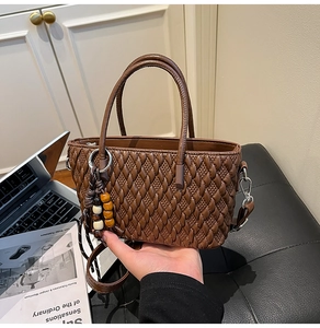 Details der dunkelbraunen Webstruktur-Eimertasche mit Holzperlen und Silberbeschlägen