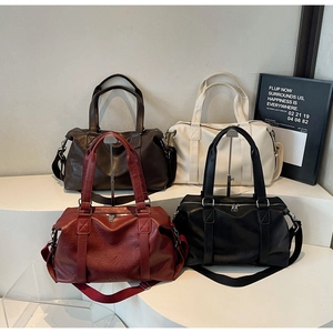 Detail view of large PU leather travel bags in four colors on minimalist geometric stands