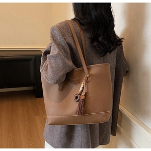 Detail of dark brown leather tote with tassel charm and textured lychee pattern