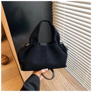 Detail of matte black suede bucket bag showing golden hardware and pleated texture